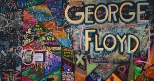 A colorful wall memorial dedicated to George Floyd has different phrases written across it in different people's handwritings with phrases such as "Black Women Matter" and "8 minutes, 46 seconds"